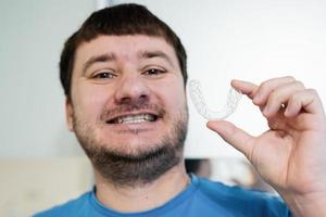 aparelho ortodôntico móvel para correção dentária. homem usando aparelho ortodôntico de silicone ou alinhador de aparelho invisível. foto