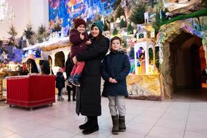 mãe com filhos visita presépio de natal na igreja. foto