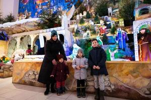 mãe com três filhos visita presépio de natal na igreja. foto