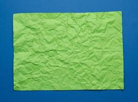 folha de papel verde amassada em branco sobre fundo azul foto