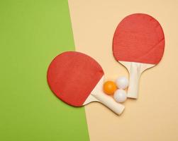 duas raquetes de madeira e uma bola de plástico laranja para jogar tênis de mesa foto