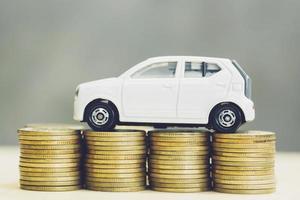 pequeno carro sobre um monte de moedas empilhadas de dinheiro. para financiamento de custos de empréstimos bancários. seguro, comprando o conceito de financiamento de carro. comprar e pagar em prestações um carro. foto