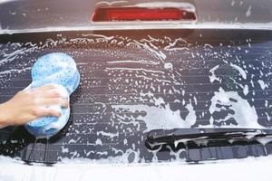 homem trabalhador de pessoas segurando a mão esponja azul e janela de limpador de espuma de bolha para lavar o carro. lavagem de carro de conceito limpa. deixe espaço para escrever mensagens. foto