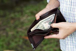 pessoa de empresário segurando uma carteira nas mãos de um homem tira dinheiro do bolso. foto