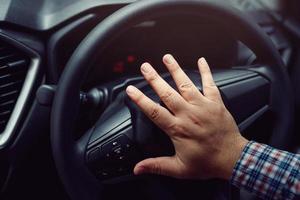 homem buzinando enquanto dirige sentado de um carro de imprensa de volante, buzinando para alertar outras pessoas foto