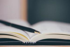 conceito de aprendizagem educacional com abertura de livro ou livro didático na biblioteca antiga, empilhe pilhas de arquivo acadêmico de texto de literatura na mesa de leitura e corredor de estantes na sala de aula de estudo da escola foto