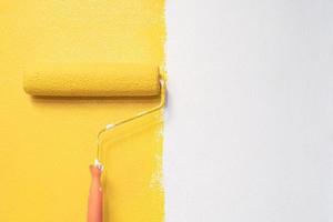 pintura com pincel de rolo, pintura de trabalhador em apartamento de pintura de parede de superfície, renovando com cor amarela foto