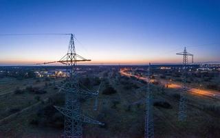 imagem panorâmica de postes de energia contra espetacular pôr do sol vermelho ao entardecer com céu sem nuvens foto