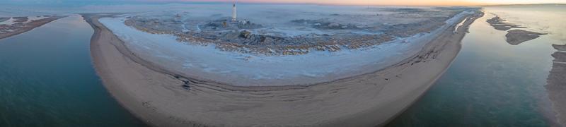 drone panorama sobre a praia e o farol do resort costeiro dinamarquês de blavand ao nascer do sol foto