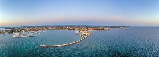 panorama drone da cidade costeira croata umag tirada durante o pôr do sol acima da entrada do porto com quebra-mar foto