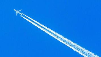 avião bimotor durante voo em alta altitude com trilhas de condensação foto