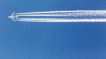 avião de quatro motores durante o vôo em alta altitude com trilhas de condensação foto