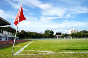 closeup bandeira vermelha em um canto de campo de futebol com céu azul brilhante. foto