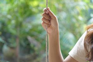 mão humana feminina segurando uma corda de balanço foto