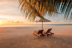 praia de férias incrível. cadeiras de casal juntos pela bandeira do mar. conceito de lua de mel de férias românticas de verão. paisagem de ilha tropical. panorama tranquilo da costa, relaxe o horizonte à beira-mar de areia, folhas de palmeira foto