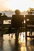 a pessoa das mulheres da silhueta relaxa sozinha em uma cadeira e desfruta da natureza tropical pela manhã com a hora do café, férias de férias, conceito de liberdade de vida. foto