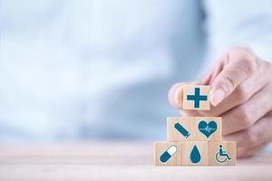 empresário escolhe um símbolo médico de saúde ícones emoticon no bloco de madeira, conceito de seguro médico e saúde