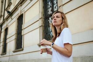 mulher caminha na rua da cidade com copo de café de papel. foto