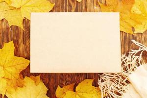 caixa de presente bege em um fundo de madeira com moldura de folhas de outono foto