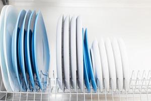 pratos limpos ficam em uma gaveta para secar pratos na cozinha foto