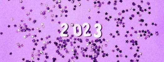 inscrição 2023 com números de madeira em fundo roxo com conceito confetti.festive multicolorido foto