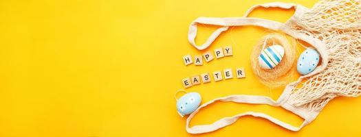 inscrição feliz páscoa com ovos pintados coloridos e saco de barbante de algodão em fundo laranja foto
