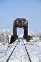trilhos na neve levam a uma ponte velha foto