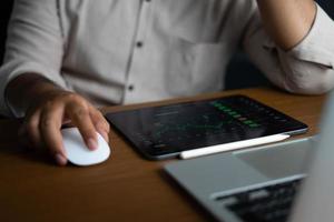 homem de negócios segurando o mouse assistindo laptop e tela de guia para monitorar a bolsa de valores foto