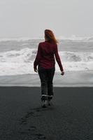 turista passando tempo na fotografia cênica da praia de reynisfjara foto