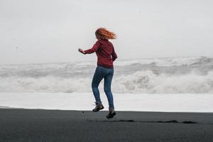 turista engraçado pulando na fotografia cênica da praia negra da Islândia foto