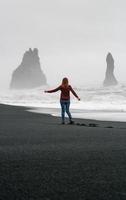 senhora apreciando a vista das rochas na fotografia cênica da praia negra da Islândia
