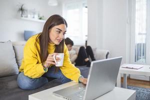 mãe multitarefa trabalhando em casa. mães podem equilibrar trabalho e família. mãe e filho usando tecnologias à mesa. família está trabalhando em laptop e tablet digital em casa. foto