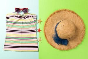 acessórios de verão com camiseta, óculos escuros, conchas e chapéu de palha na vista superior do plano de fundo foto
