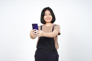 tire uma selfie usando o smartphone de uma linda mulher asiática isolada no fundo branco foto