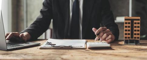 empresários, empresários, contadores, corretores de imóveis, um jovem usando uma calculadora para calcular seu orçamento doméstico para avaliar os riscos de investir em imóveis. foto