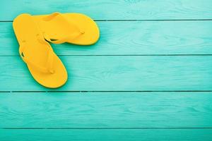 chinelos amarelos sobre fundo azul de madeira. férias de verão. vista do topo. brincar. espaço de cópia foto