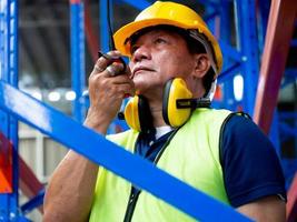 masculino pessoal pessoa engenheiro vestir amarelo fone de ouvido capacete de segurança capacete talkie walkie armazém terminal carga construção comercial falar trabalhos emprego ocupação indústria técnico de construção trabalho de fábrica foto