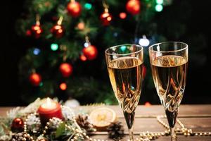 copos de champanhe espumante no fundo de uma árvore de natal decorada. humor de ano novo foto