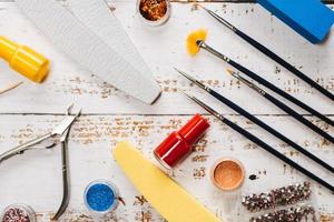 conjunto de ferramentas de manicure e esmaltes em um fundo branco de madeira. foto