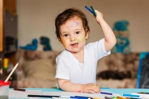 menino bonitinho segurando marcadores e lápis de cor foto