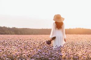 uma linda garota em um campo de lavanda. uma linda mulher no estilo provençal em um vestido branco com um buquê nas mãos. foto