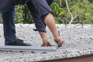 trabalho masculino eletricista instalar trilho de alumínio. configuração de trabalhador técnico profissional conectar metal elétrico na casa do telhado para célula solar foto