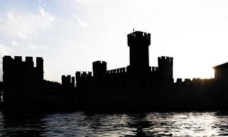 itália - silhueta do castelo sirmone no lago garda ao pôr do sol. arquitetura medieval com torre. foto
