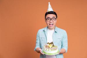 jovem asiático segurando o bolo de aniversário foto