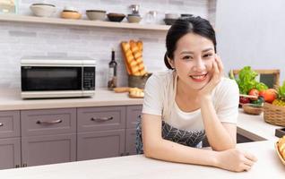 jovem mulher asiática se preparando para cozinhar na cozinha foto
