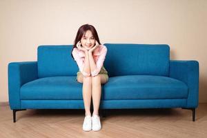 imagem de uma jovem mulher asiática sentada no sofá foto