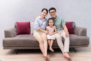 jovem família asiática sentada no sofá foto