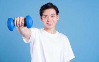 jovem asiático segurando halteres no fundo foto