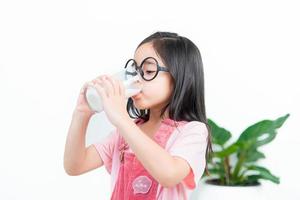 criança ásia menina beber leite com um copo foto