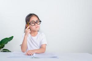 retrato da pequena aluna escrevendo na mesa no estudo de aluna fazendo teste na escola primária. crianças escrevendo notas em sala de aula. conceito de conhecimento de educação foto